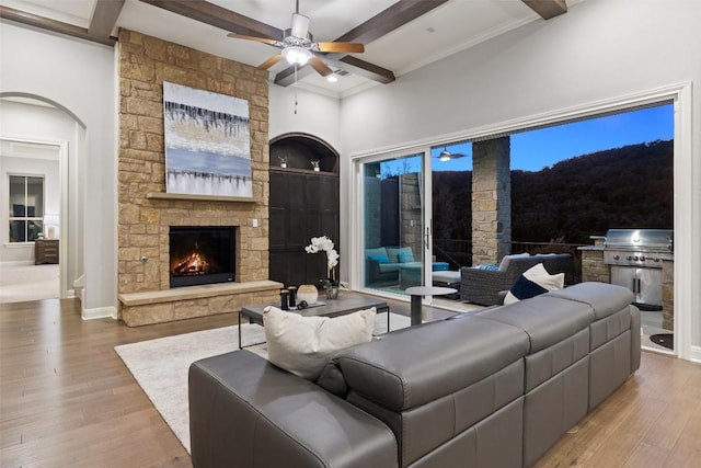 living room featuring a fireplace, beamed ceiling, and light wood-type flooring