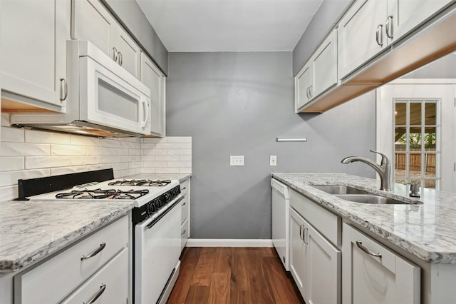 kitchen with white cabinetry, sink, white appliances, and light stone counters