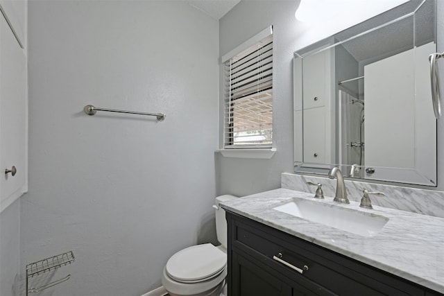 bathroom featuring vanity, walk in shower, and toilet