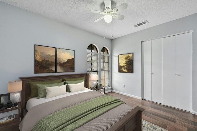 bedroom featuring ceiling fan, a textured ceiling, dark hardwood / wood-style flooring, and a closet