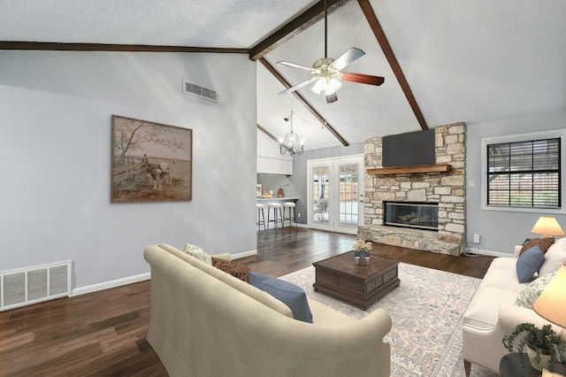 living room with a stone fireplace, dark hardwood / wood-style floors, ceiling fan with notable chandelier, a textured ceiling, and beam ceiling