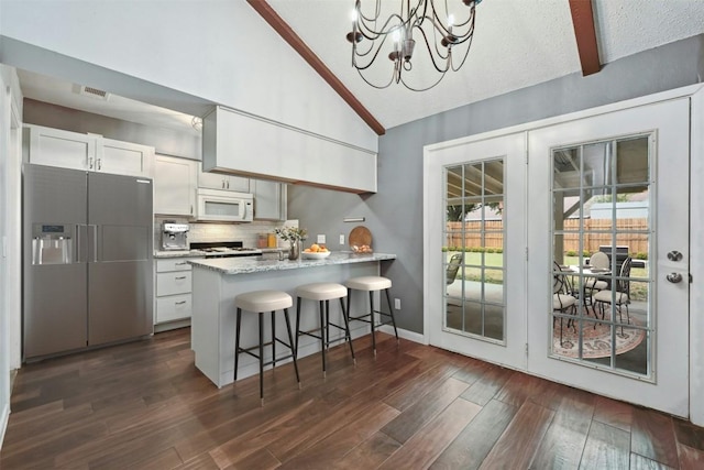 kitchen with a breakfast bar area, white cabinetry, fridge with ice dispenser, dark hardwood / wood-style flooring, and kitchen peninsula