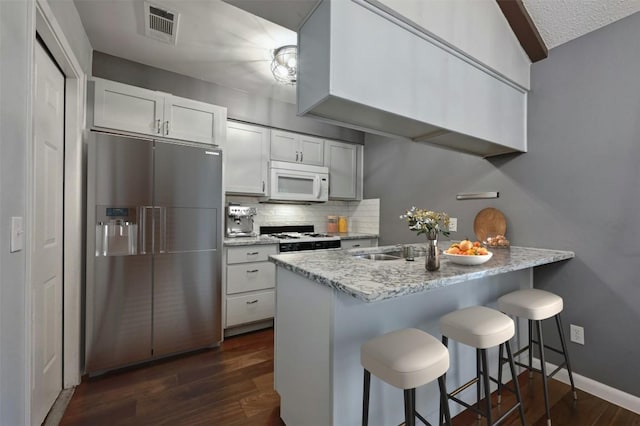 kitchen featuring white cabinetry, white appliances, kitchen peninsula, and a breakfast bar