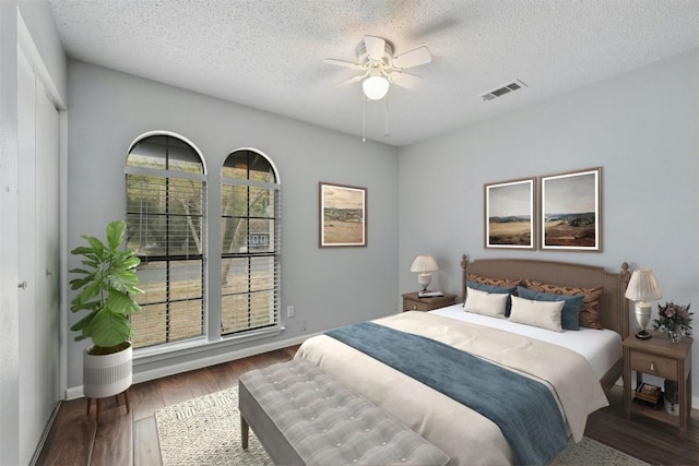 bedroom with ceiling fan, wood-type flooring, and a textured ceiling