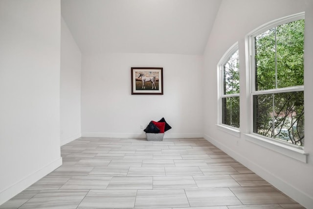 spare room with plenty of natural light, vaulted ceiling, and baseboards