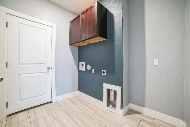 laundry room featuring a textured wall, hookup for an electric dryer, cabinet space, and baseboards