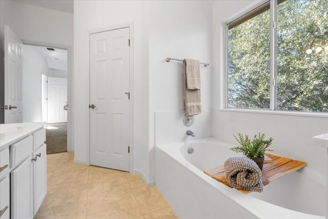 bathroom featuring tile patterned flooring, vanity, a tub, and a healthy amount of sunlight