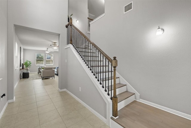 stairway with a high ceiling, tile patterned floors, and ceiling fan