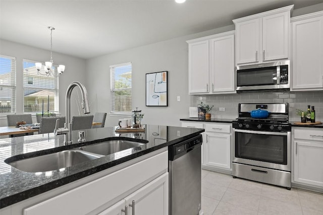 kitchen with sink, appliances with stainless steel finishes, dark stone countertops, tasteful backsplash, and white cabinets