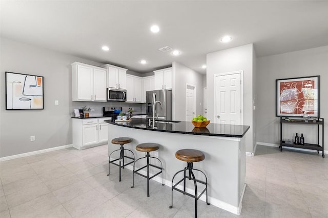 kitchen featuring white cabinetry, sink, stainless steel appliances, and an island with sink