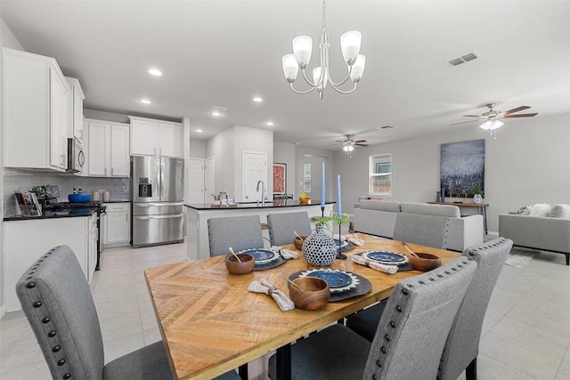 tiled dining space featuring ceiling fan with notable chandelier and sink