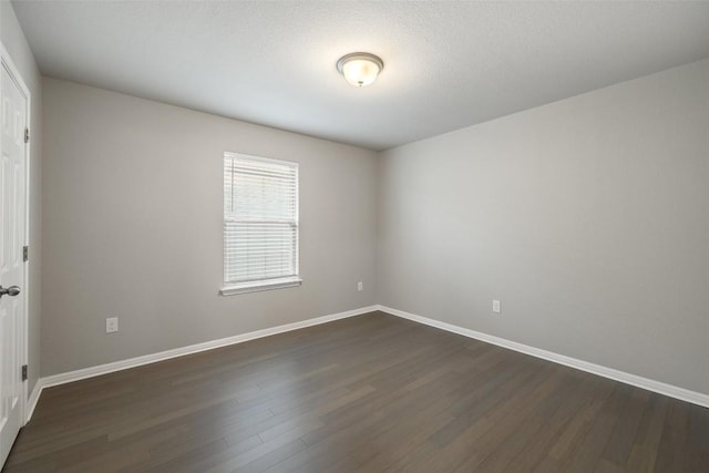 empty room with dark hardwood / wood-style flooring and a textured ceiling