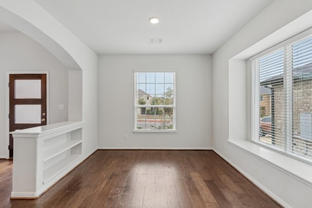 empty room with dark wood-type flooring and a healthy amount of sunlight