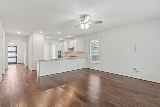 kitchen featuring white cabinetry, dark hardwood / wood-style floors, light stone counters, decorative backsplash, and kitchen peninsula