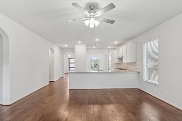 interior space with sink, dark hardwood / wood-style floors, kitchen peninsula, light stone countertops, and white cabinets