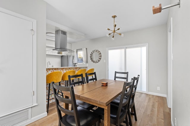 dining space with light hardwood / wood-style flooring and a chandelier