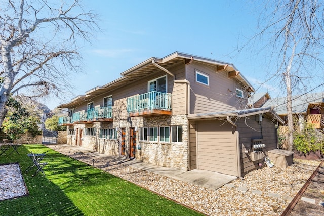 back of house with a balcony and a yard