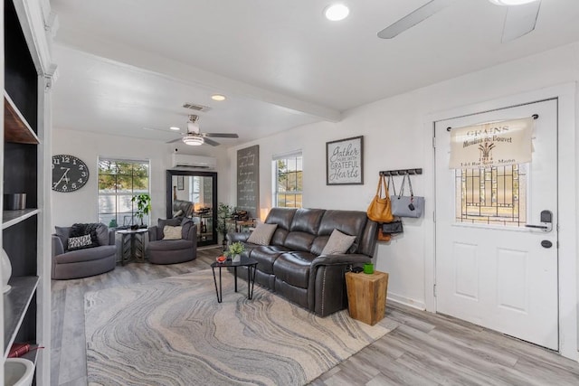 living room with ceiling fan, a wall mounted air conditioner, beam ceiling, and light hardwood / wood-style floors