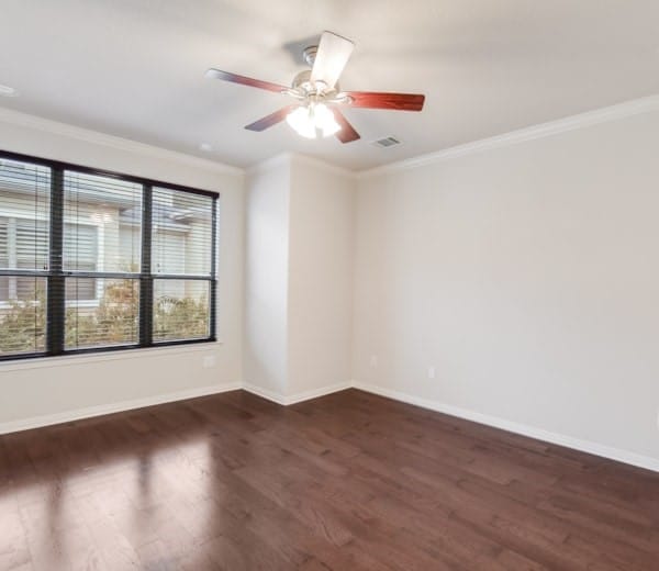 spare room featuring dark hardwood / wood-style flooring, ornamental molding, and ceiling fan