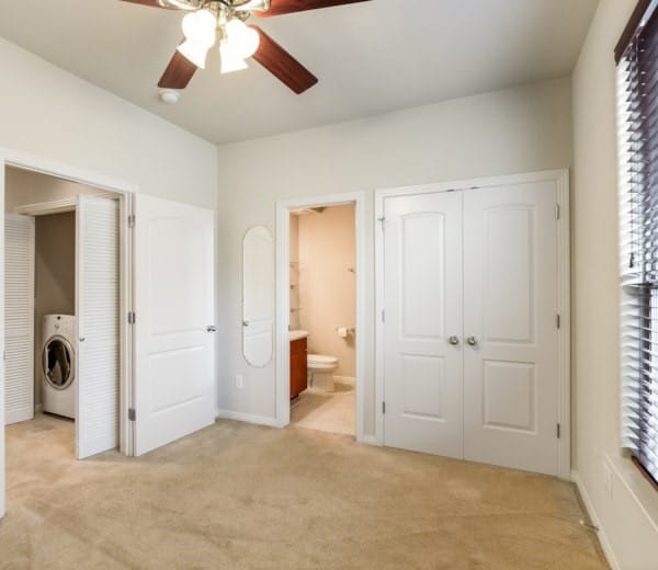 unfurnished bedroom featuring ensuite bath, washer / clothes dryer, a closet, and light carpet