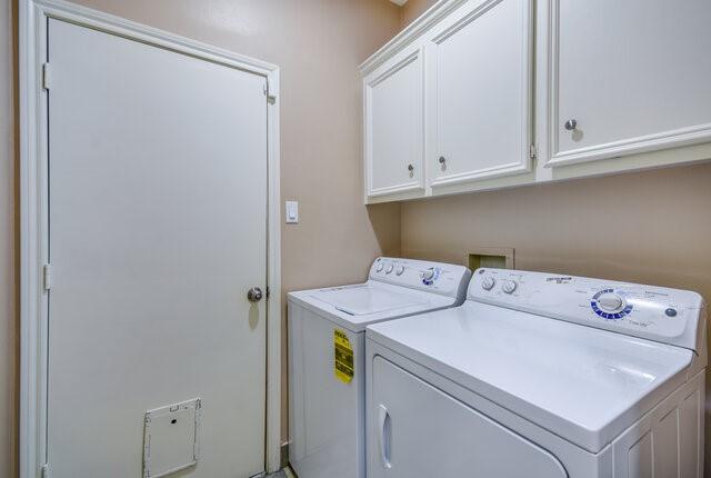 clothes washing area with cabinets and washer and clothes dryer