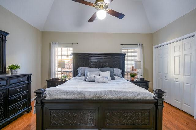 bedroom with ceiling fan, a closet, vaulted ceiling, and light hardwood / wood-style floors