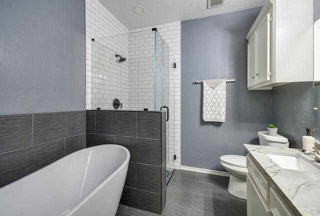 full bathroom with tile patterned flooring, toilet, shower with separate bathtub, a textured ceiling, and vanity