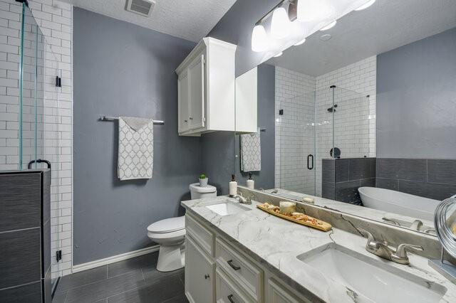 full bathroom with a textured ceiling, vanity, tile patterned flooring, and shower with separate bathtub