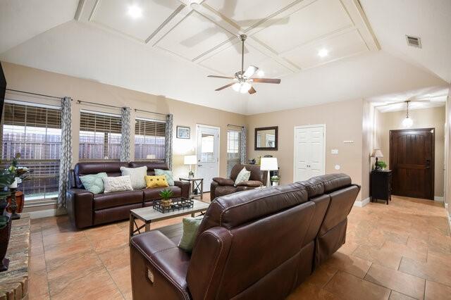 living area featuring baseboards, visible vents, coffered ceiling, lofted ceiling with beams, and ceiling fan