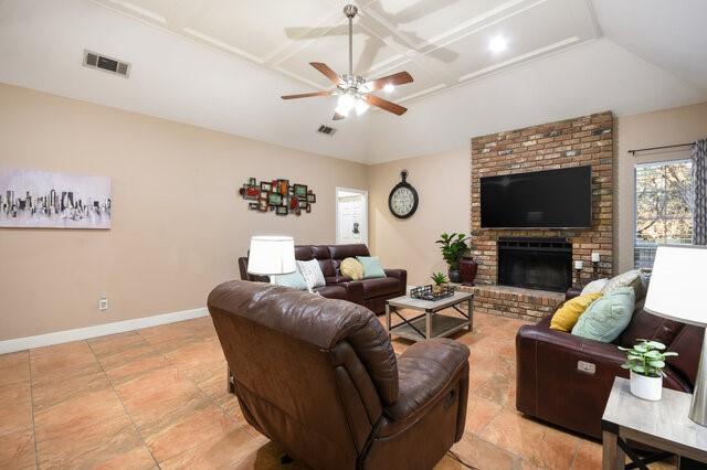 living room with coffered ceiling, a brick fireplace, and ceiling fan