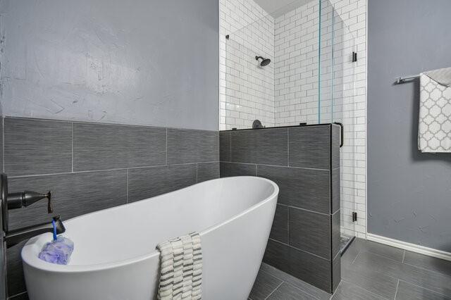 full bath featuring a freestanding bath, tile walls, a stall shower, and tile patterned flooring