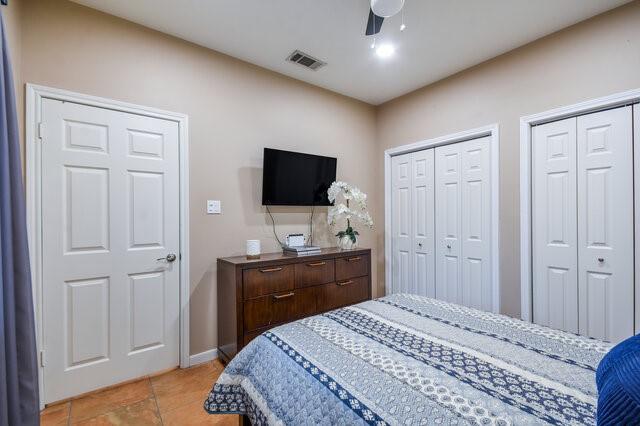 bedroom with two closets, ceiling fan, and light tile patterned floors