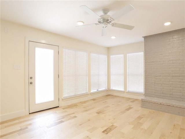 interior space featuring ceiling fan, brick wall, and light wood-type flooring