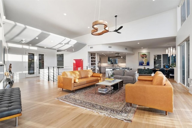 living room featuring a towering ceiling, light wood-type flooring, and french doors