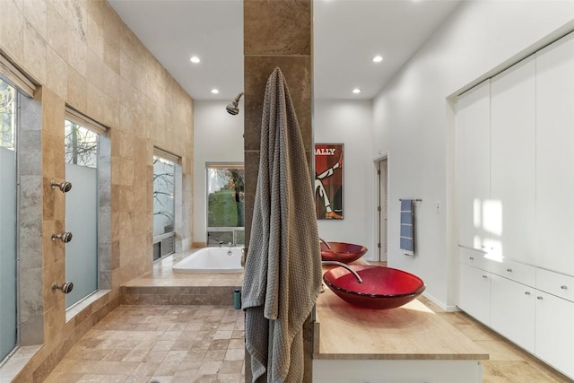 bathroom featuring shower with separate bathtub, sink, and tile walls