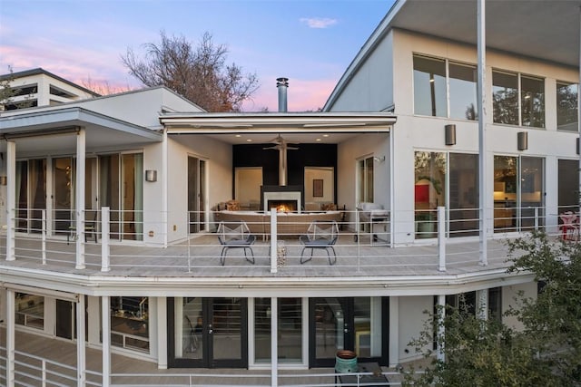 2102 N Oak Canyon Rd, Austin, TX 78746 - rear view of house featuring a lit fireplace, stucco siding, a ceiling fan, and a patio area