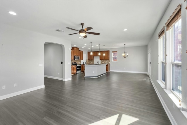 unfurnished living room featuring dark wood-type flooring and ceiling fan with notable chandelier