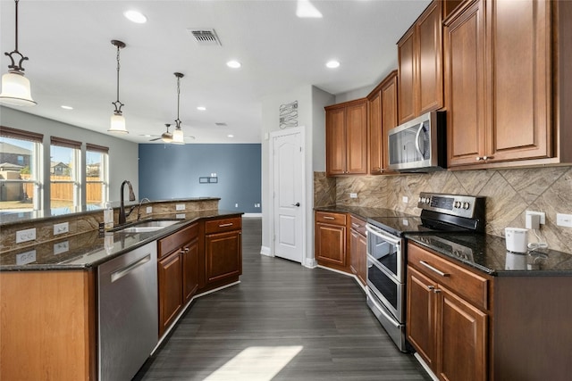 kitchen featuring sink, tasteful backsplash, appliances with stainless steel finishes, dark hardwood / wood-style floors, and pendant lighting