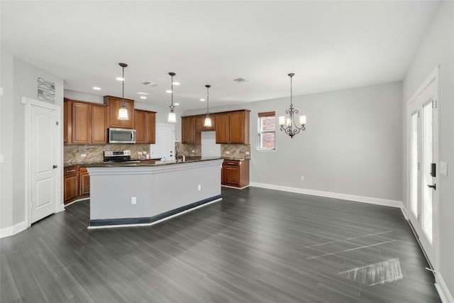 kitchen with tasteful backsplash, an inviting chandelier, a center island, hanging light fixtures, and appliances with stainless steel finishes