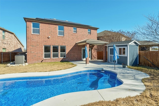 view of pool featuring a patio, central AC unit, a shed, and solar panels