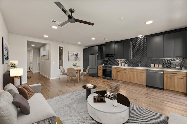 living room with ceiling fan, sink, and light wood-type flooring