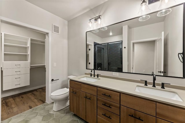 bathroom featuring tile patterned flooring, vanity, toilet, and walk in shower