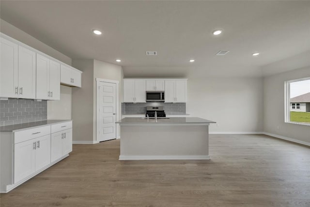 650 Radley Rd, Lockhart, TX 78644 - kitchen featuring white cabinetry, appliances with stainless steel finishes, a center island with sink, and light wood-type flooring