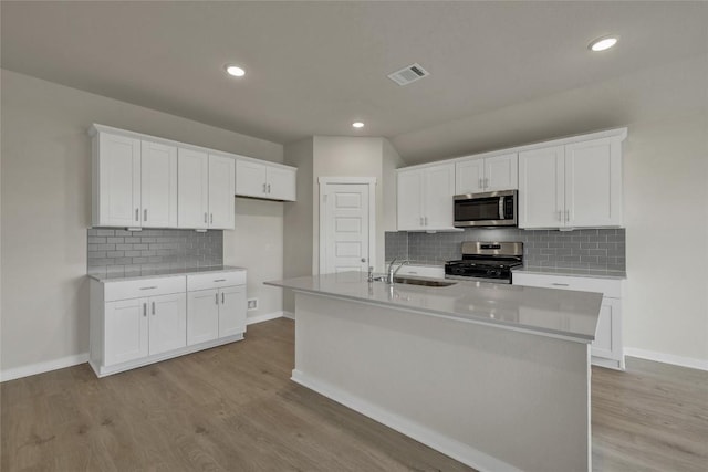 650 Radley Rd, Lockhart, TX 78644 - kitchen featuring stainless steel appliances, tasteful backsplash, an island with sink, white cabinets, and light wood-type flooring