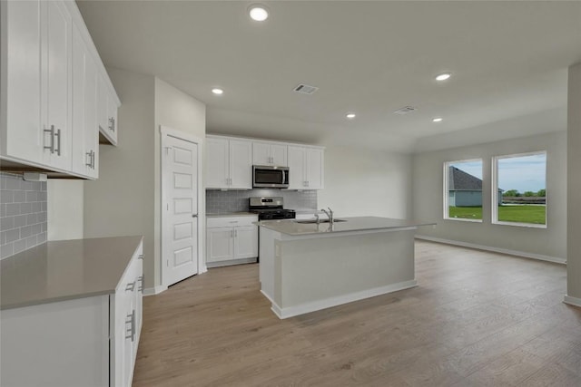 650 Radley Rd, Lockhart, TX 78644 - kitchen with appliances with stainless steel finishes, an island with sink, light hardwood / wood-style flooring, and white cabinets