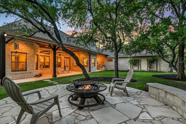 patio terrace at dusk featuring a yard and an outdoor fire pit