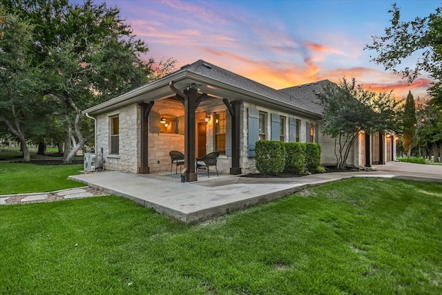 back house at dusk featuring a yard and a patio area