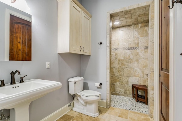 bathroom with toilet, sink, and a tile shower