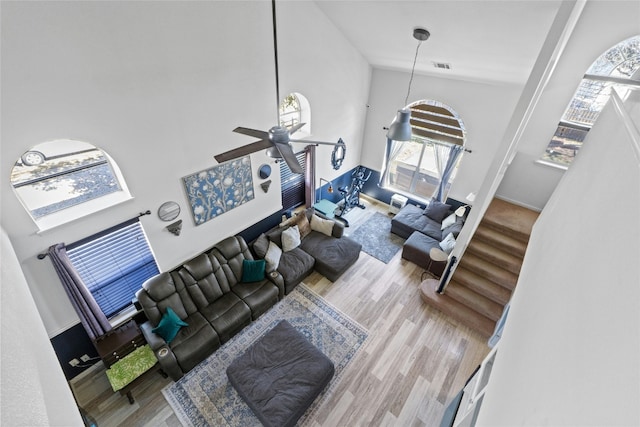 living room with ceiling fan, hardwood / wood-style floors, and a high ceiling