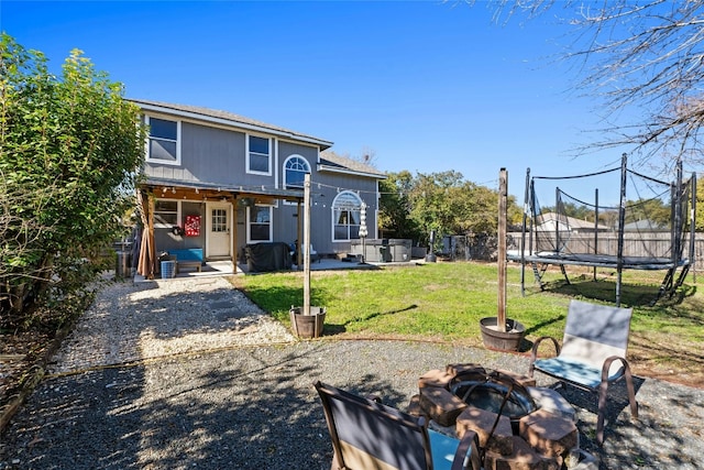 back of house with a trampoline, a yard, a patio area, and an outdoor fire pit